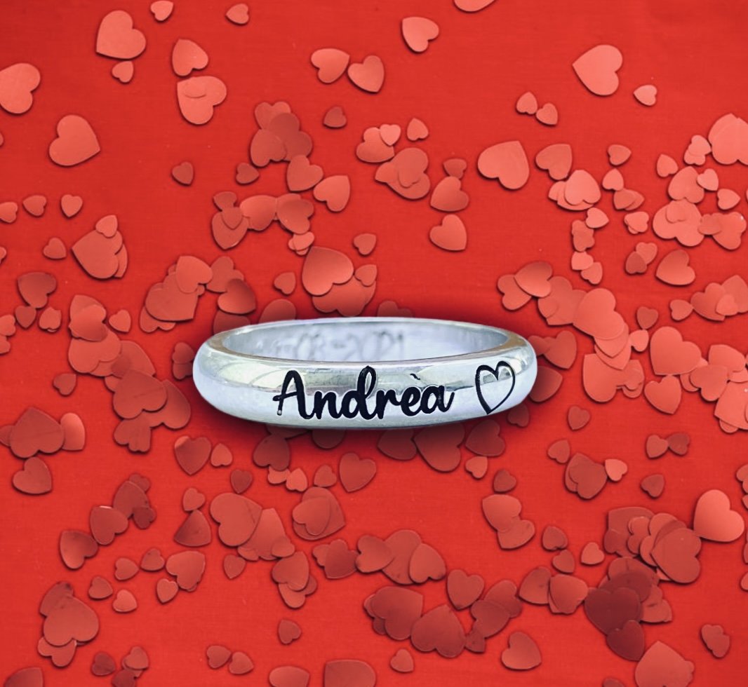 Fedina con nome inciso e cuoricino su sfondo a cuori.