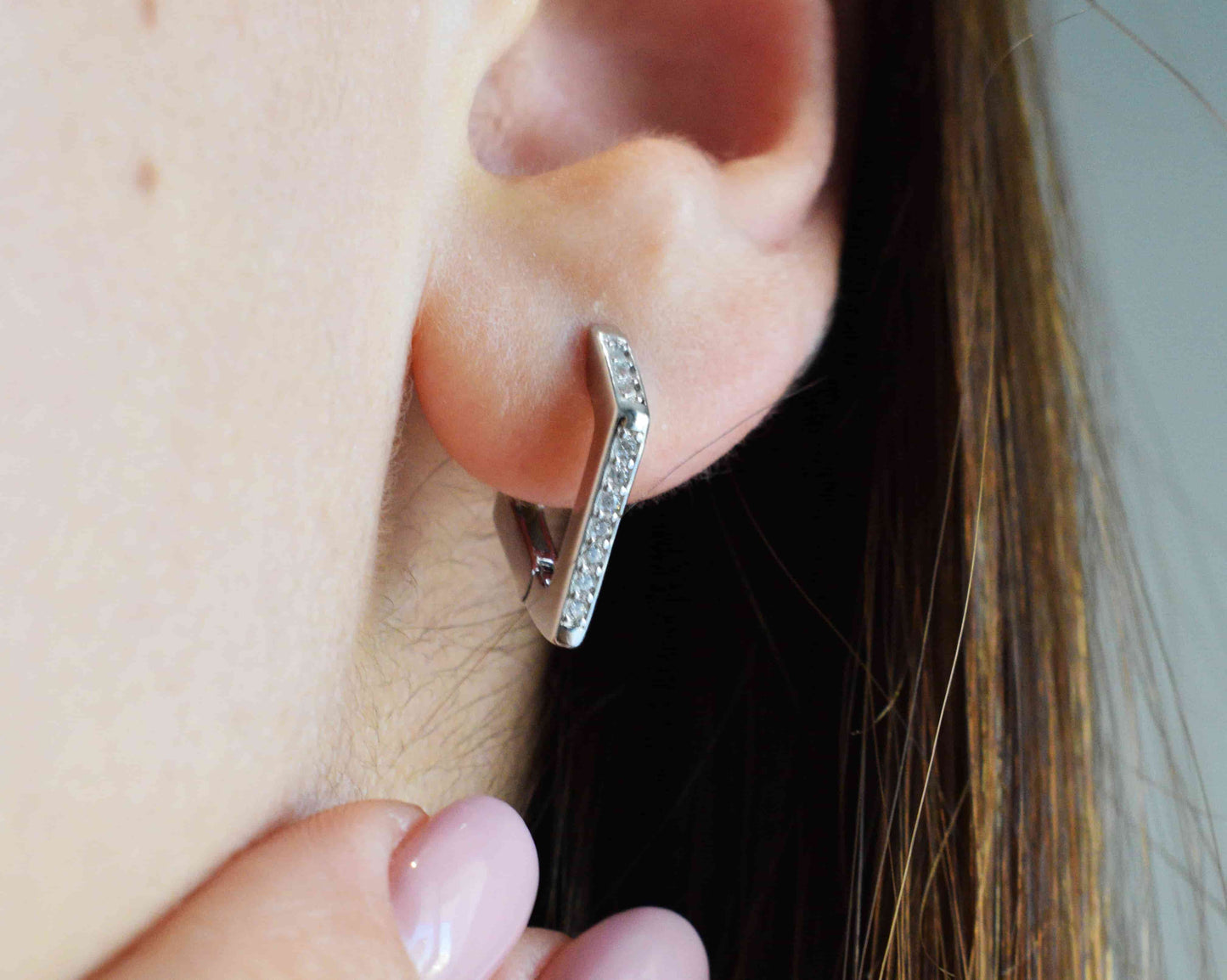 Orecchini a spigoli indossati in argento 925 e zirconi.