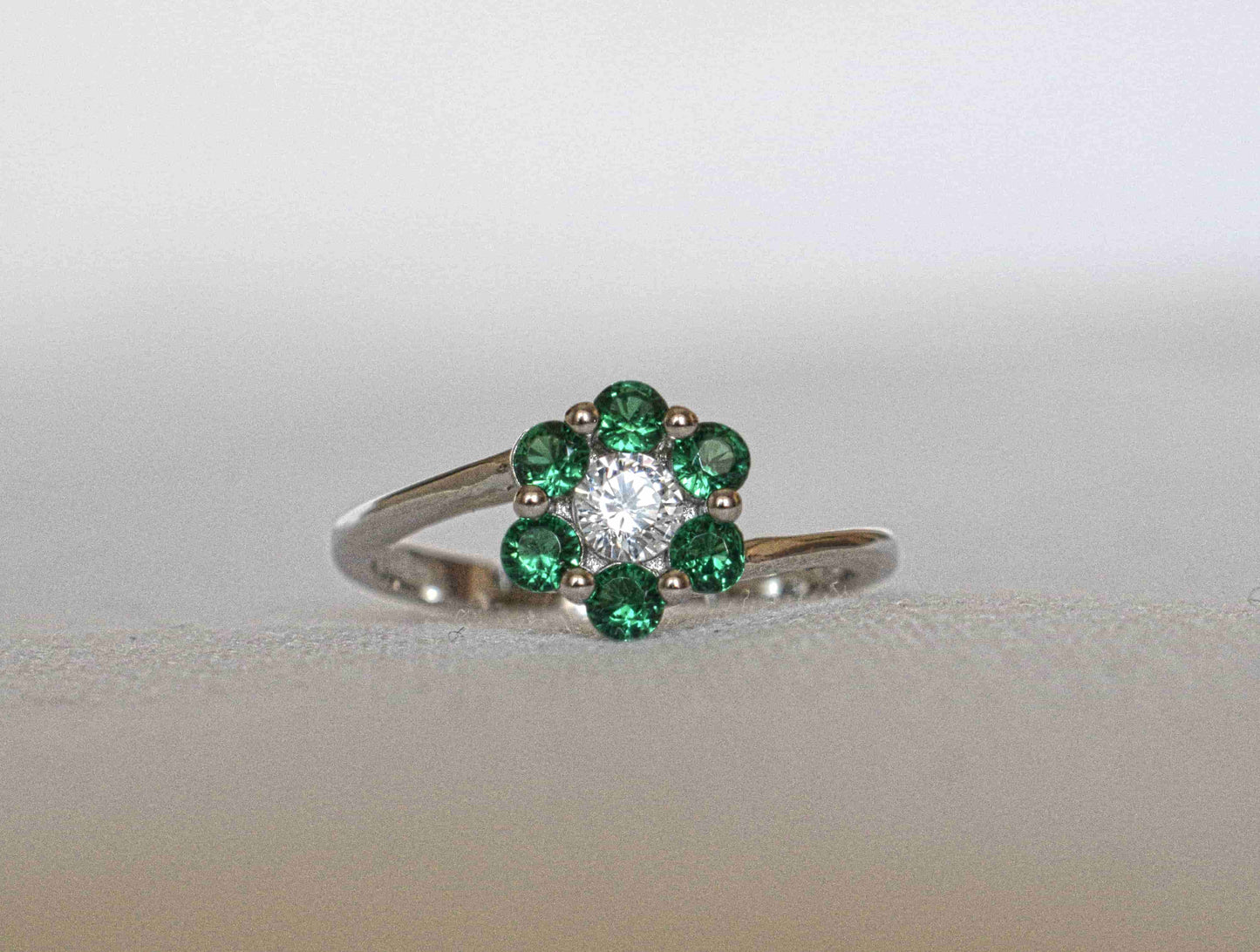 Anello Fiore Solitario in argento 925 con zircone trasparente al centro e contornato da zirconi verdi che compongono la forma di un fiore.