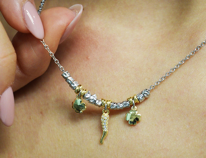 Collana portafortuna indossata con peperoncino e quadrifoglio placcati in oro.